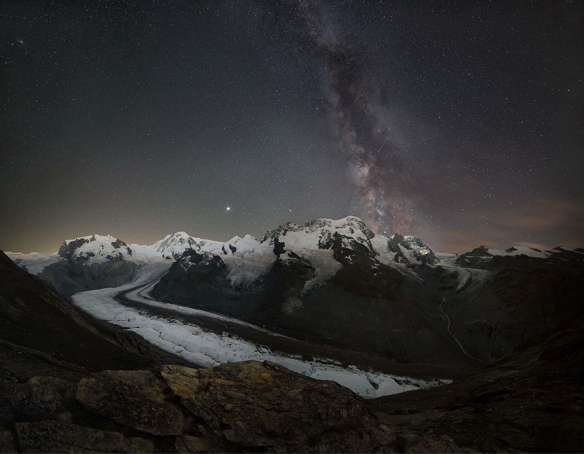 Die Monte Rosa Bergkette mit dem Gornergletscher auf dem Gornergrat bei Nacht unter der Milchstraße mit einer Perseiden Sternschnuppe.