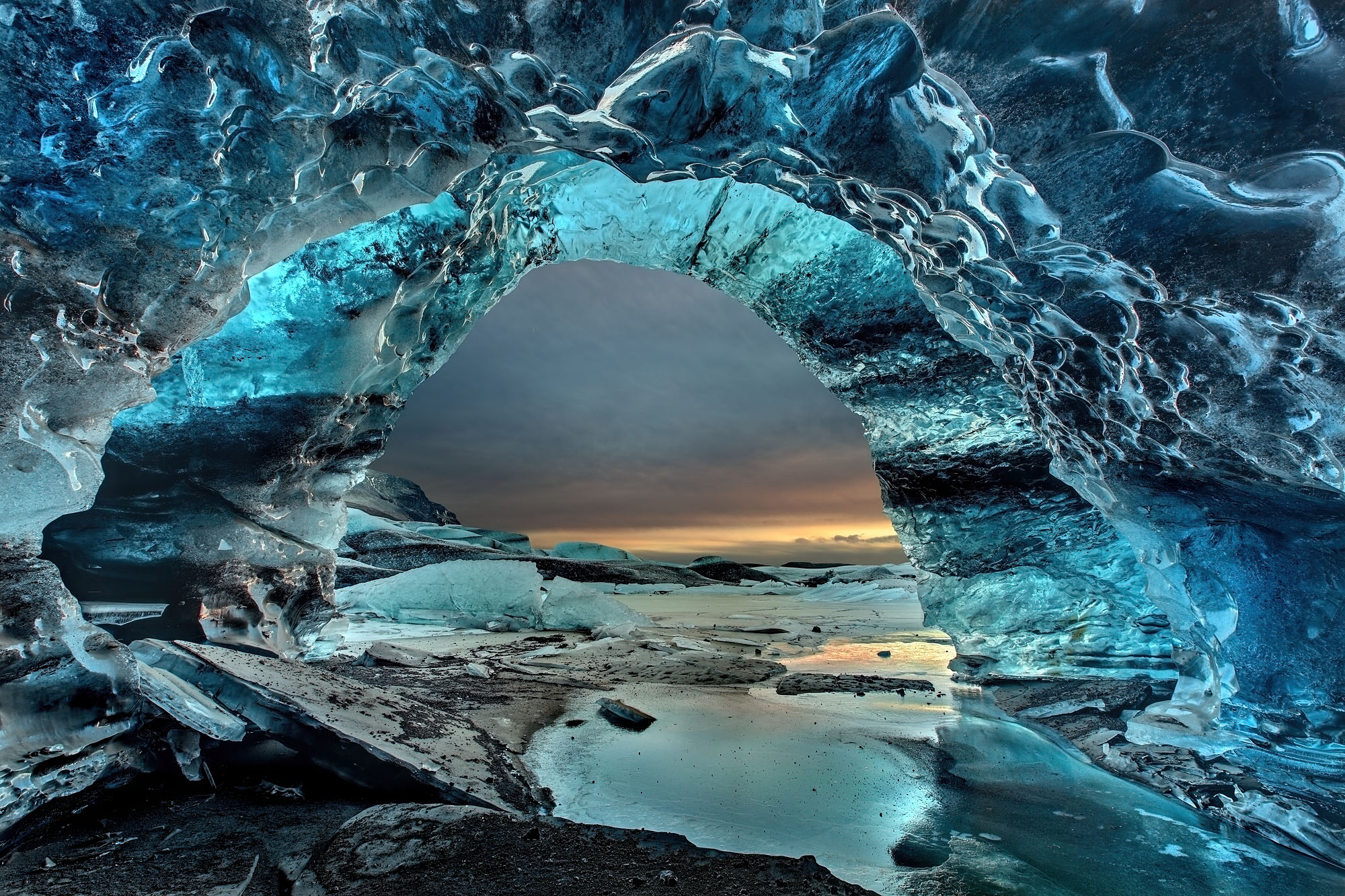 Riesige tiefblaue Eishöhle im Svínafellsjökull Gletscher in Skaftafell, Island mit Blick auf den Sonnenuntergang.
