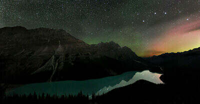 Rote und grüne Polarlichter flackern lautlos über den sternenklaren Nachthimmel über dem Peyto Lake in den kanadischen Rocky Mountains bei Banff.