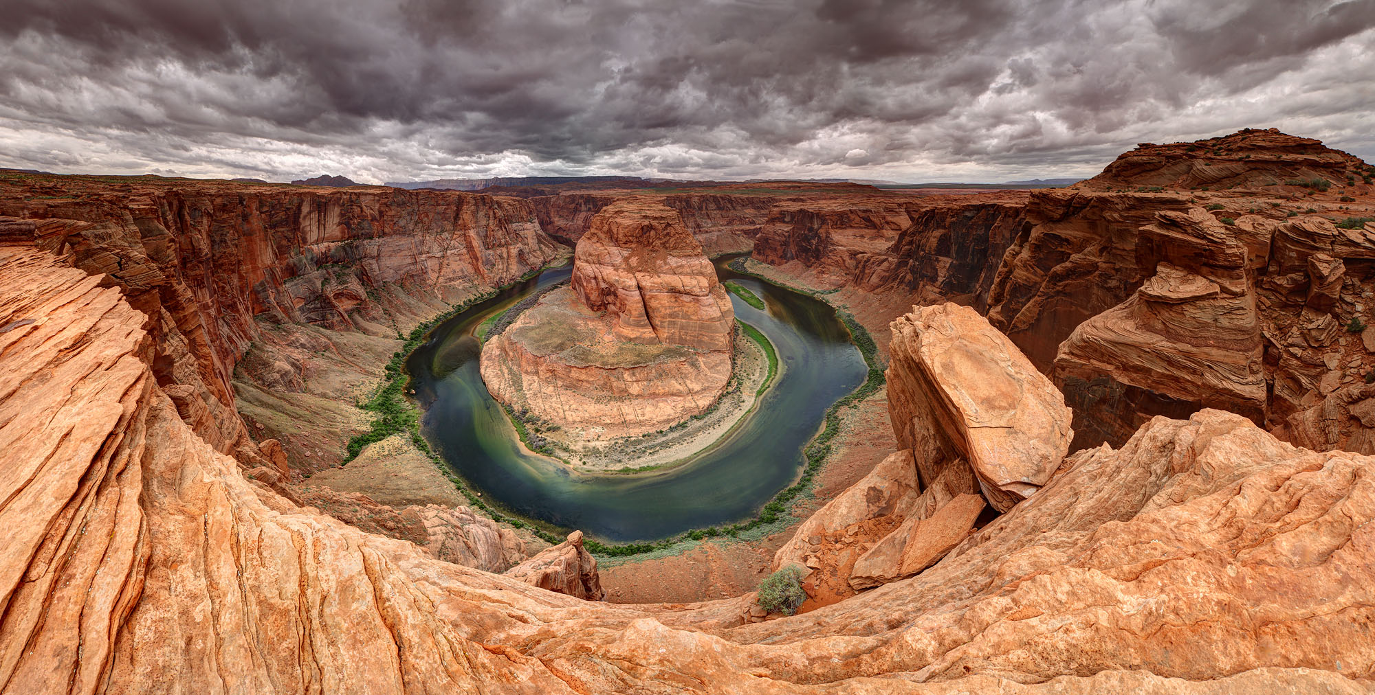 The thunderstorm skies over Horseshoe Bend show an incised meander of the Colorado River downstream of Glen Canyon and Lake Powell near Page in Arizona and marks the entrance to the Grand Canyon.