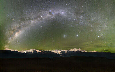 Green Southern Lights envelop the arc of the Milky Way over the New Zealand Alps with Mount Cook and Mount Tasman in an enchanting light
