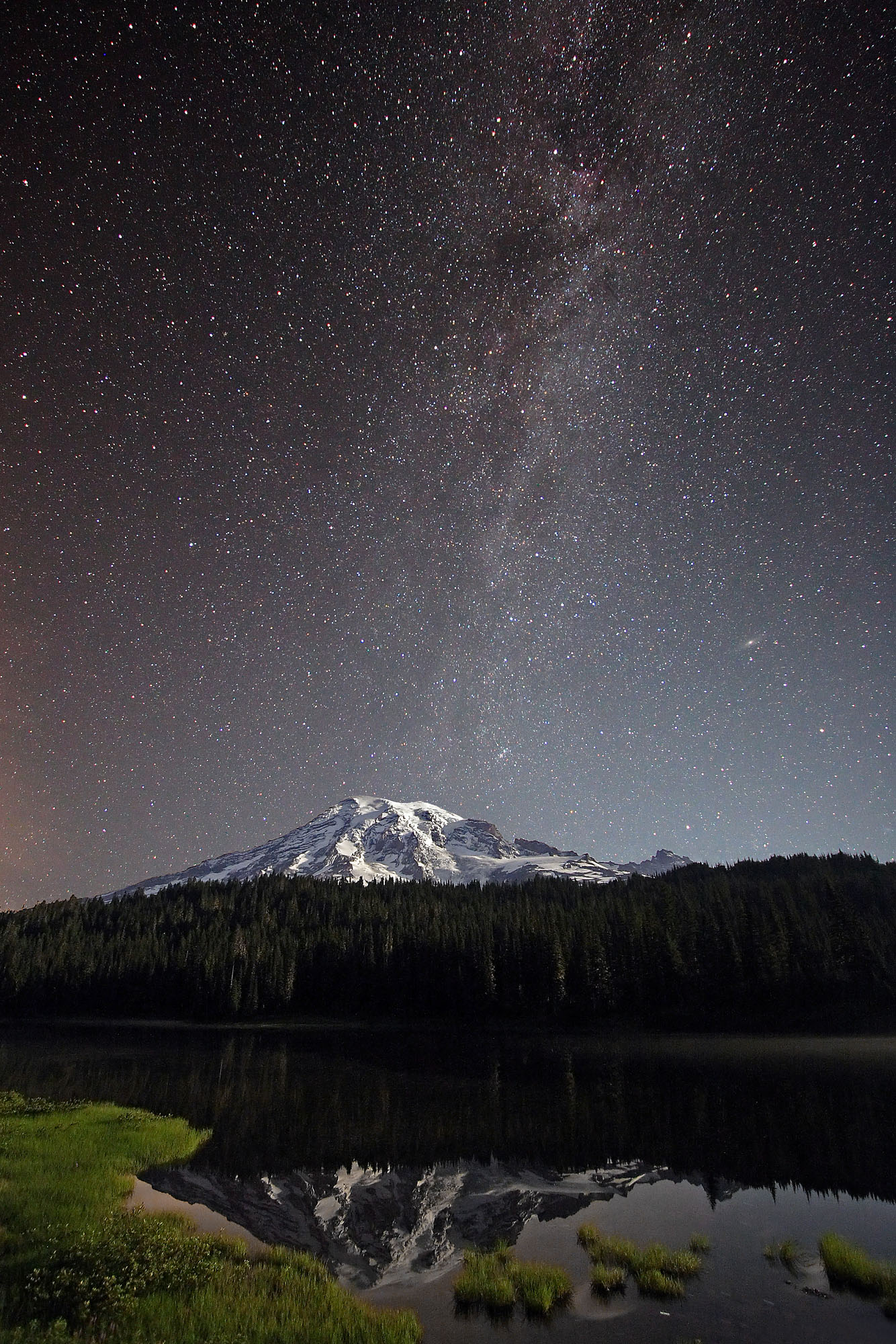 Nighttime Mount Rainier volcano mirrors with the stars of the Milky Way in the Reflection Lakes