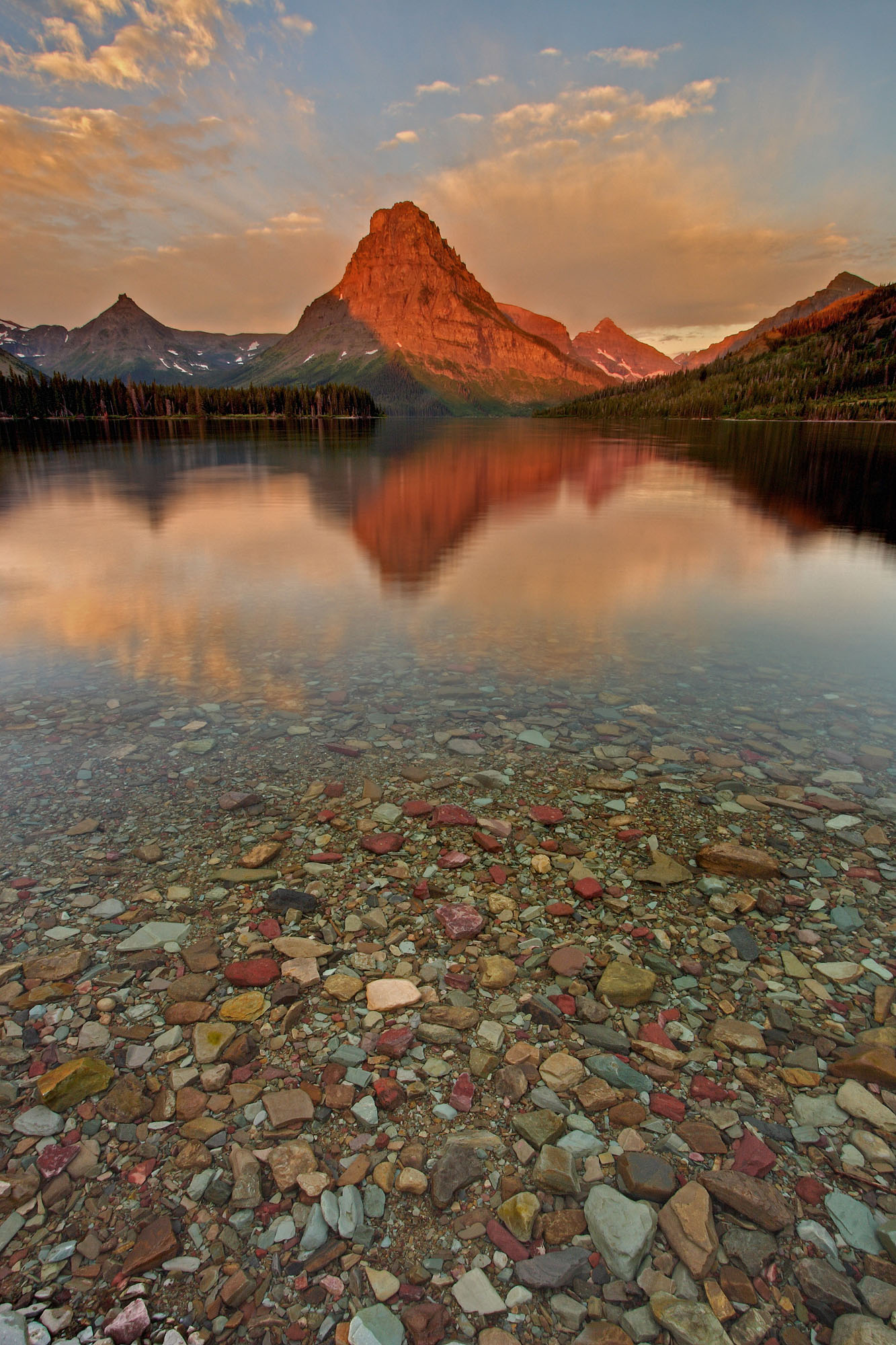 Sinopah Mountain mirrors in Two Medicine Lake in Waterton Glacier National Park, Wyoming with ancient pebbles