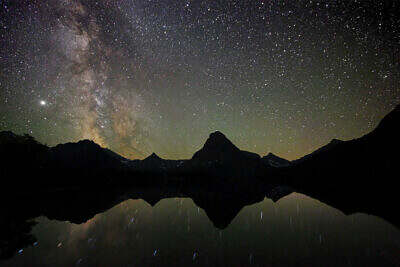 The Milky Way rises over Sinopah Mountain in Waterton Glacier, Montana, and is reflected in Two Medicine Lake at new moon